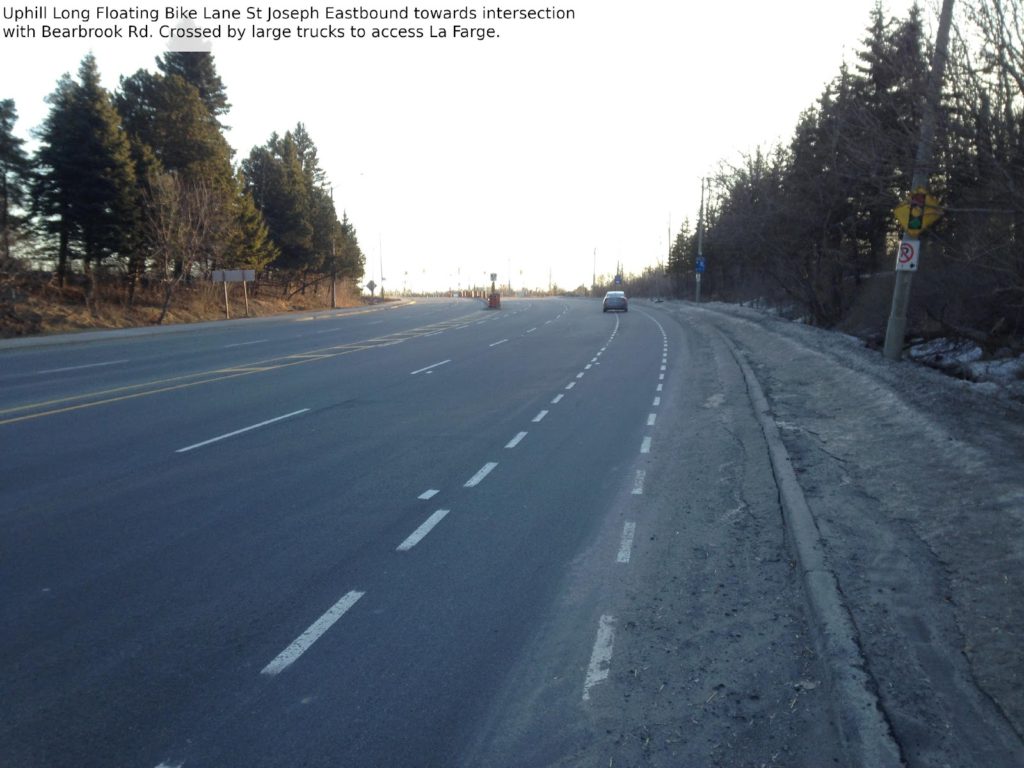 Uphill long floating bike lane St Joseph eastbound toward intersection with Bearbrook Rd. Crossed by large trucks to access LaFarge.