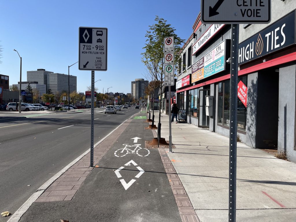 Picture show the cycle track heading between many signs and tree covers. 