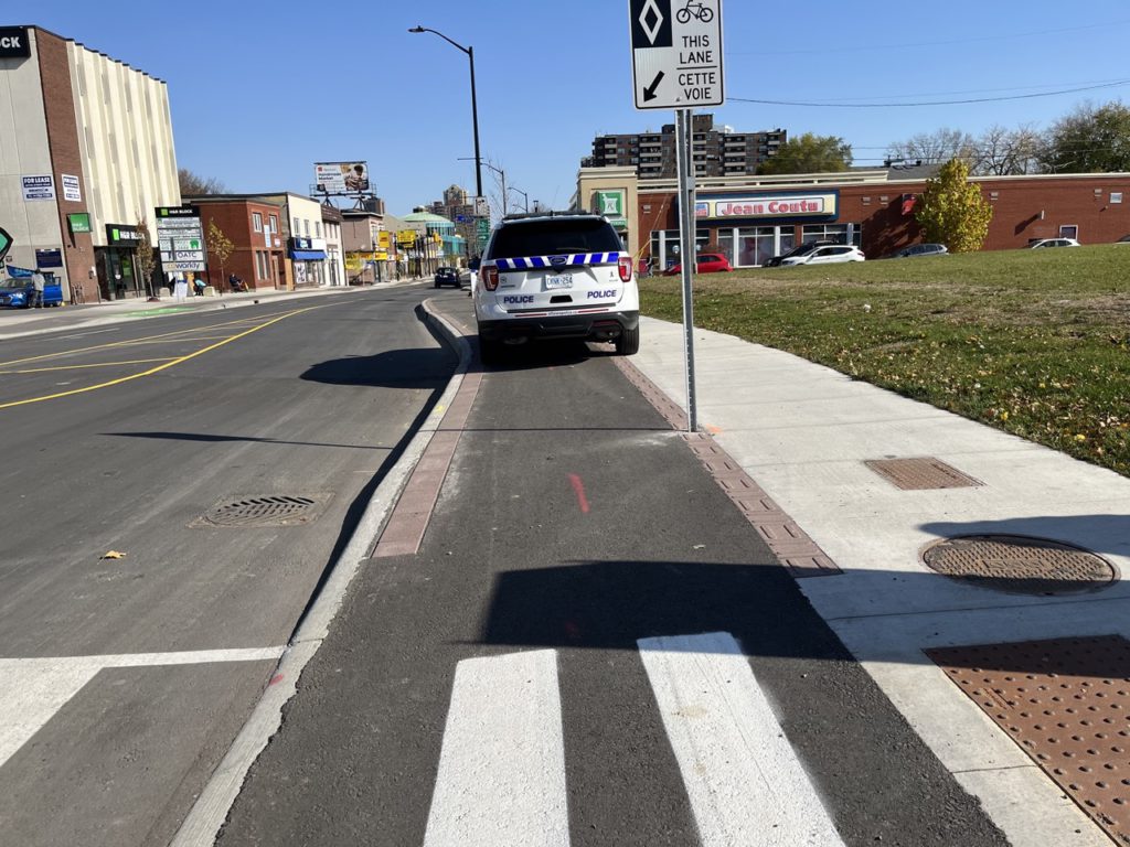 Image shows: New bike lanes christened on the day of opening by someone parking in them- and Ottawa Police SUV.