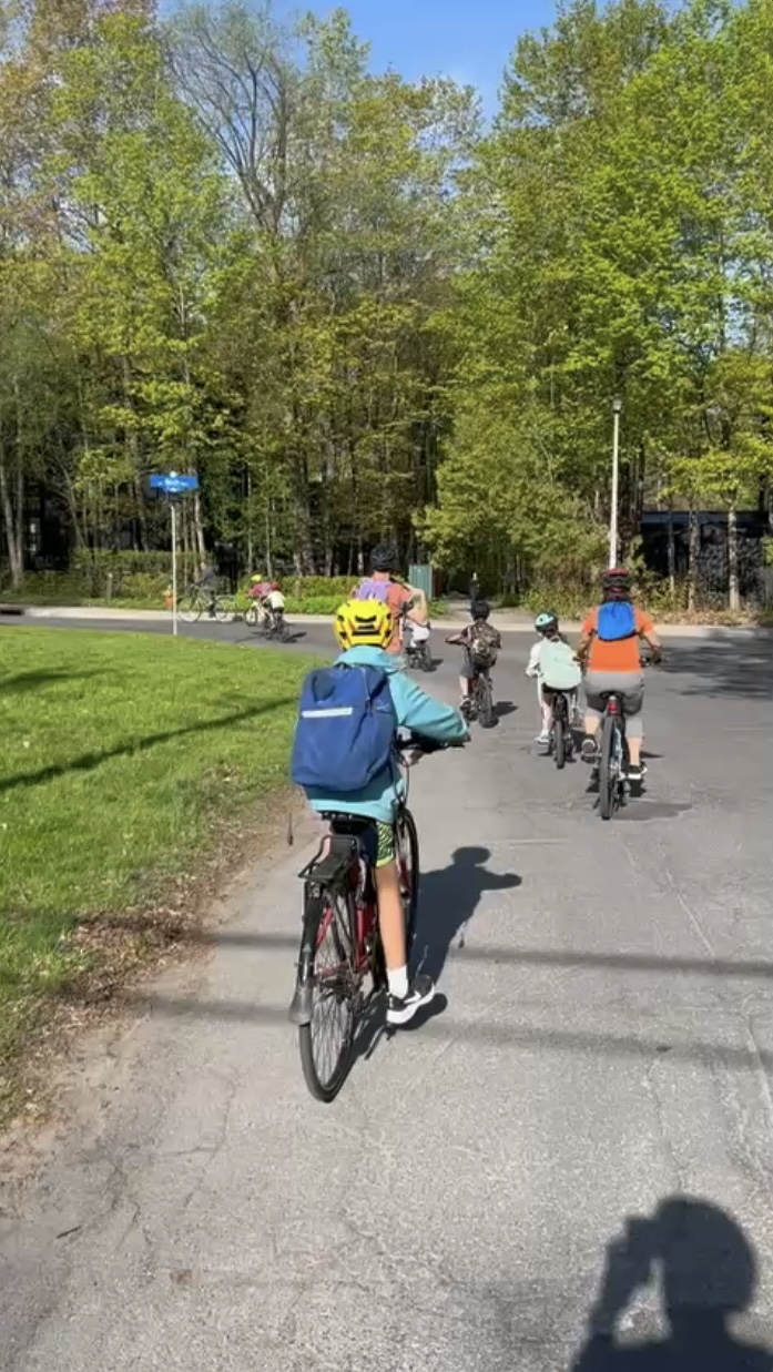 Des enfants et parents quittent le dernier point de passage du vélo-bus et tournent à gauche en arrière-plan.