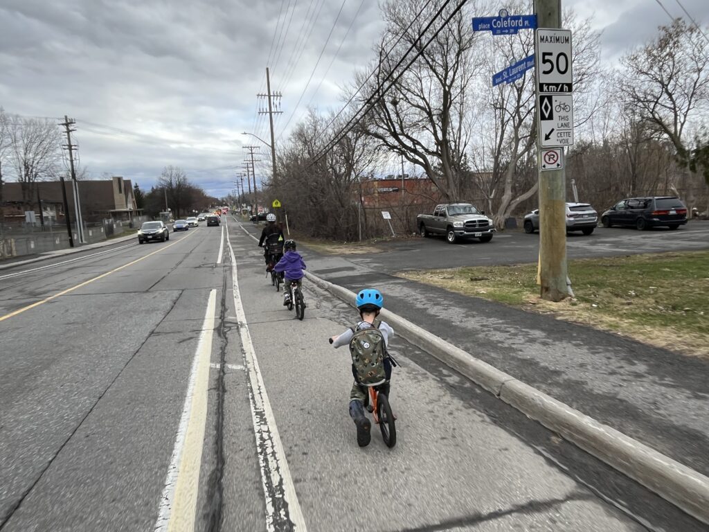 Bike bus rolling down Saint-Laurent single file in a painted bike lane.