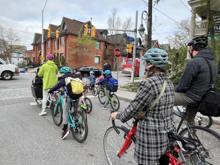 Adult and kids on bikes waiting behind the stop line at a red traffic light