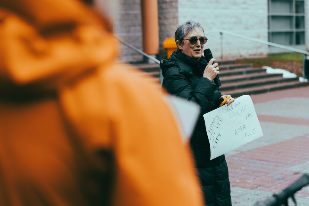 Florence Lehmann from Bike Ottawa addressing the Bill 60 rally. She’s holding a sign that reads: hands off my city and touche pas à ma ville.