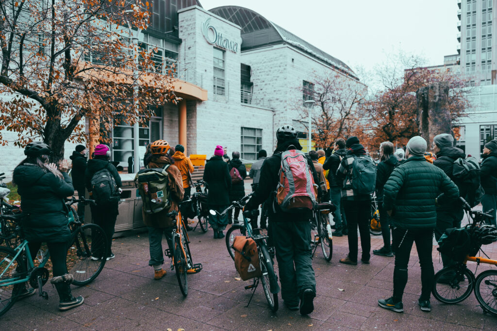 People listening to a speaker at the Bill 60 rally as seen from the back. Ottawa city hall in the background