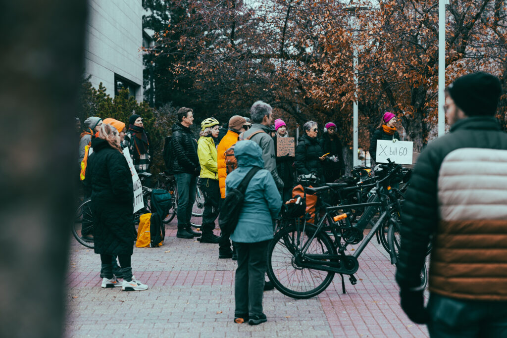 Crowd listening to a speaker at the bill 60 rally. Some are with their bikes.